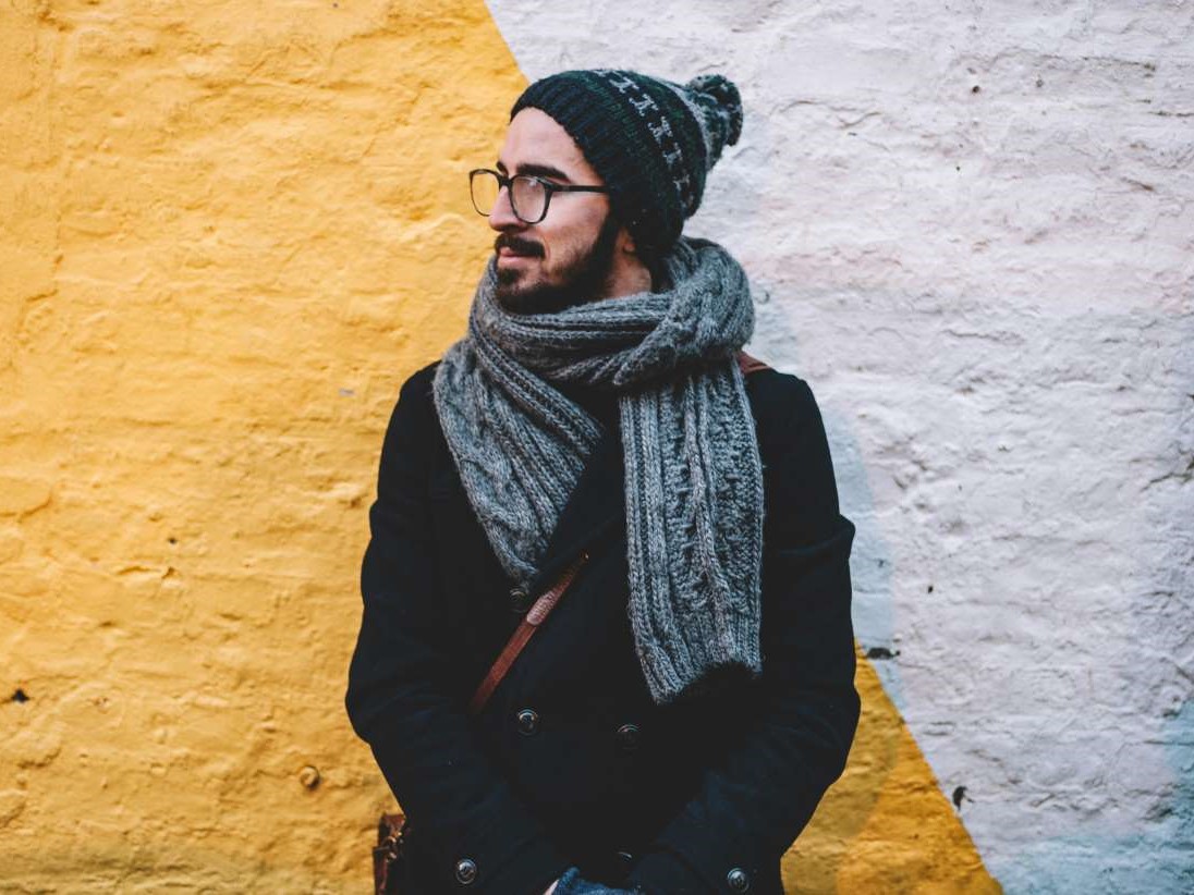 a man with a skully hat and scarf looking away from the camera