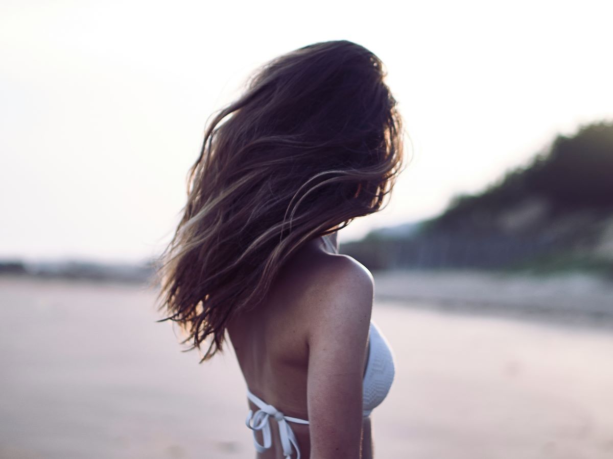 a woman at the beach with the wind blowing her hair